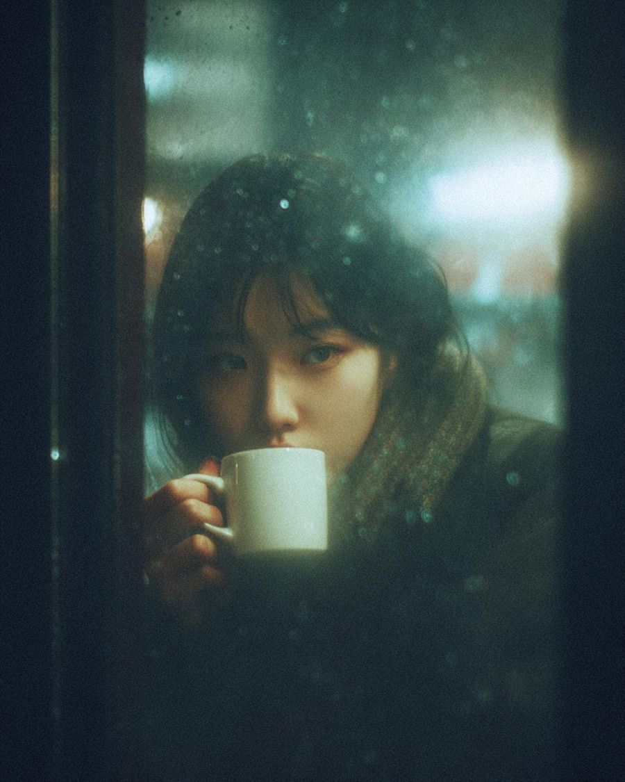 Cinematic, Moody Photograph of a Young Woman Sitting Inside a Café — Nano Banana Pro image prompt example
